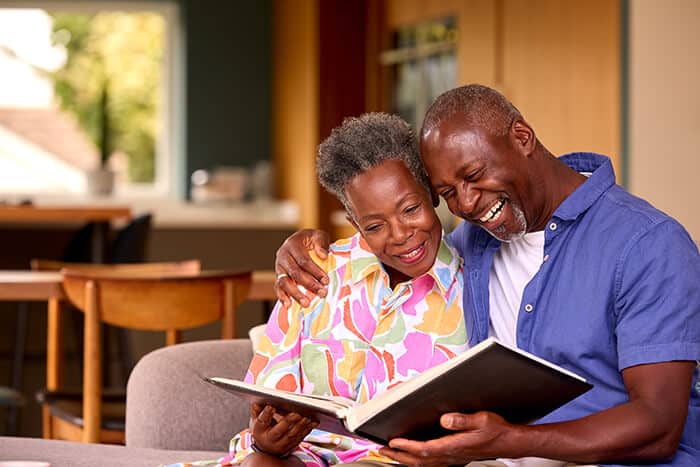 Couple laughing and reading a book on a couch